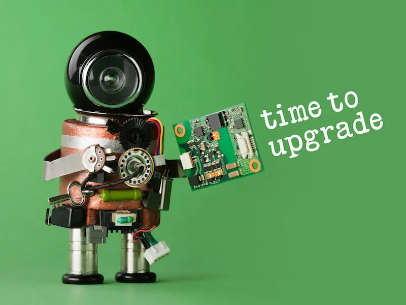 A robot made of electronic parts holds a computer circuit board against a green background. White text reads, time to upgrade.