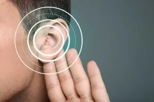 A close-up of a person’s ear with concentric digital circles over it, suggesting hearing or sound waves, while a hand is cupped behind the ear as if trying to listen more closely.